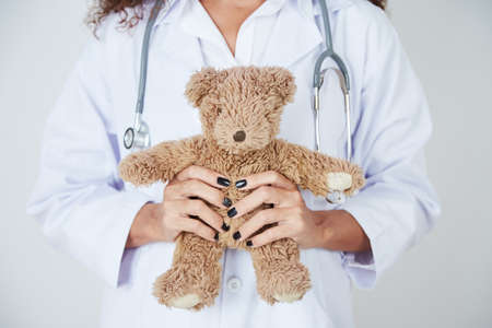 Close-up of female woman in white gown holding teddy bear in her handsの写真素材