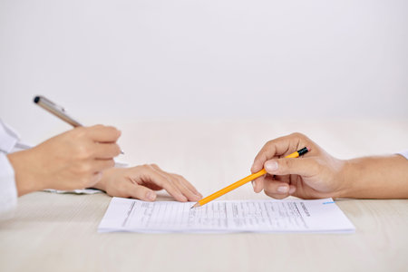 Crop side view of people signing contract at table sitting in front of each other