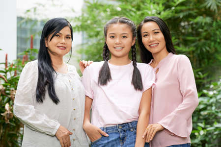 Group of Asian women and teenage girl of one family embracing and looking at cameraの写真素材