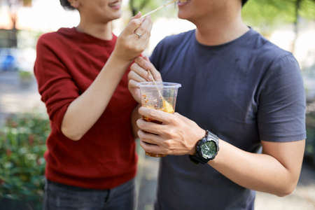 Cropped image of couple eating delicious street food outdoorsの写真素材