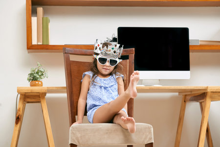 Little princess playing on chair in office of parent
