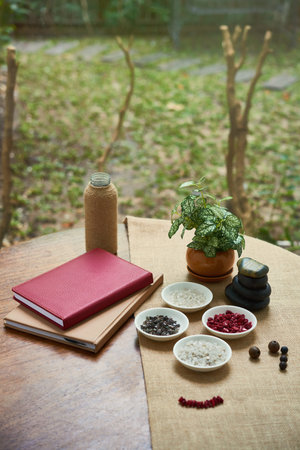 Image of books and plates with colored stones and unfinished bracelet from stone bead are on the...