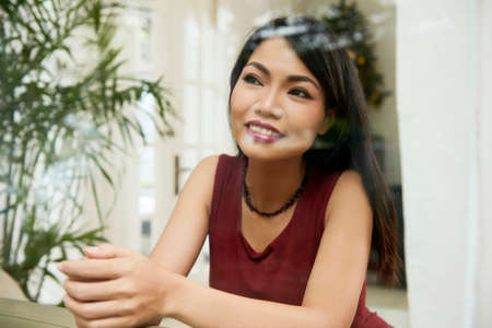 Beautiful Asian woman resting on sofa in the room and looking out the windowの写真素材