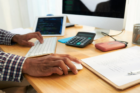 Hand of mix-raced programmer or manager clicking on mouse button while computing by desk in office