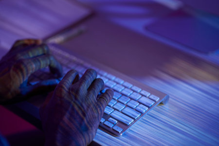 Human hands with reflection from monitor typing on keypad in front of computer screen