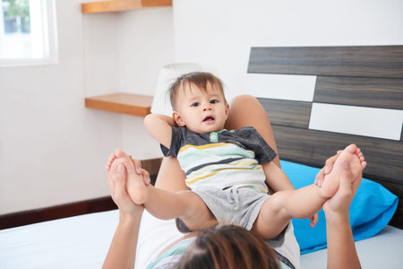 Mother lying on bed and playing with her cute little son