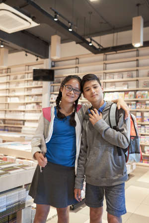 Portrait of hugging brother and sister in school libraryの写真素材
