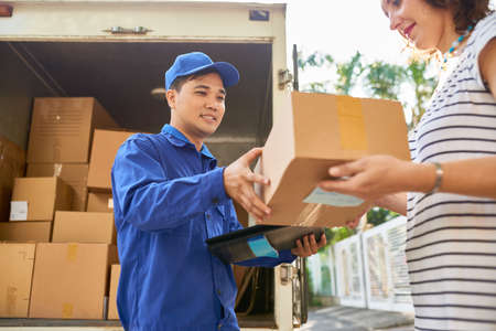 Smiling Asian courier delivering parcel to young womanの写真素材