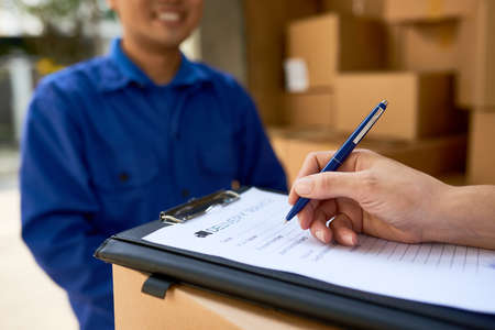Female client ordering truck to deliver packages with her stuff and filling documentの写真素材