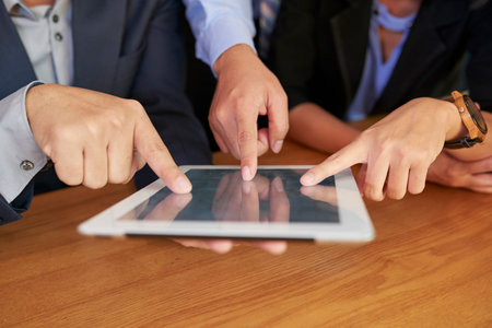 Close-up image of business people pointing at tablet computerの写真素材