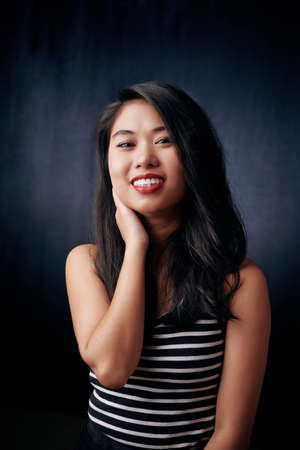 Portrait of Asian beautiful girl smiling and looking at camera isolated on black backgroundの写真素材