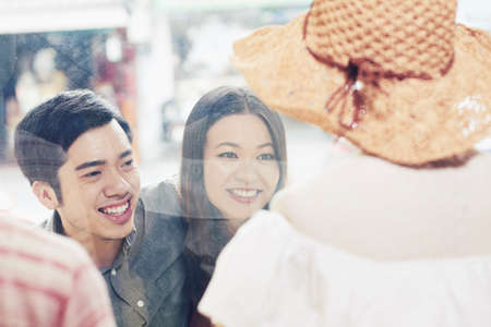 Smiling young Vietnamese couple looking at clothes from news collection in shop window of fashion boutiqueの写真素材