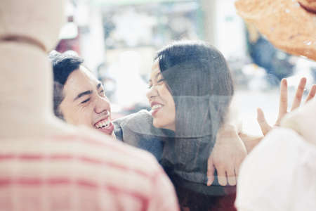 Laughing joyful guy young couple standing at shop window of fashion boutiqueの写真素材