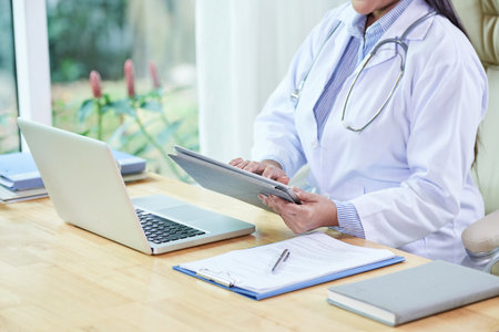 Cropped image of female doctor reading e-mails on tablet computer