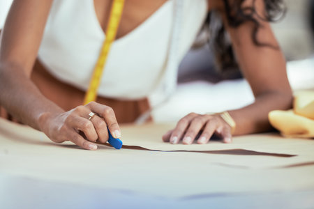 Close-up image of seamstress outlining paper pattern of dress on fabric