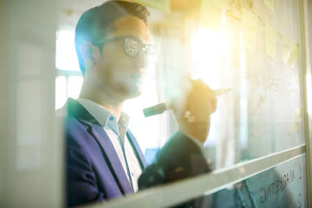 Businessman drawing ideas for innovative project on glass wall in officeの写真素材