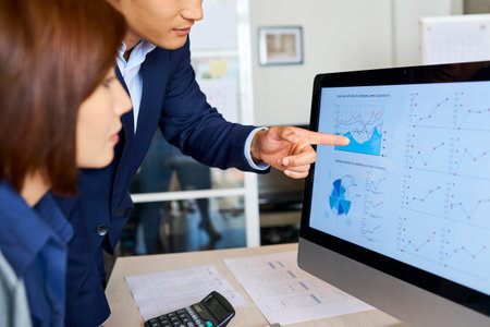 Professional financial analysts discussing diagrams of computer screen