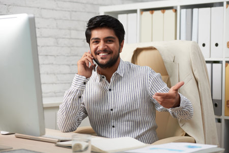 Portrait of smiling Indian businessman with smartphone