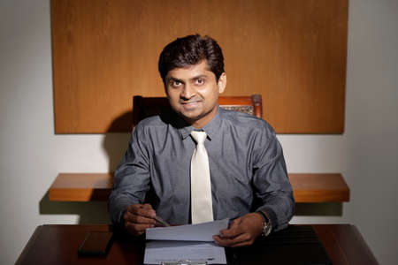 Smiling businessman working with documentsの写真素材