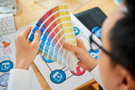 Hands of graphic designer using palette when choosing colors he needsの写真素材