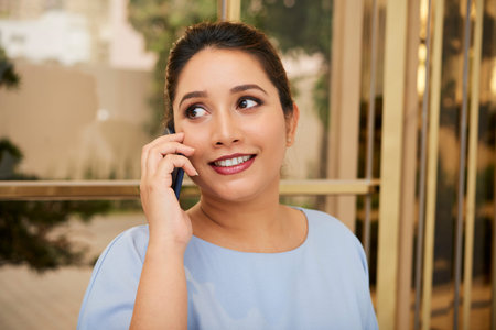 Attractive smiling Indian entrepreneur answering phone call
