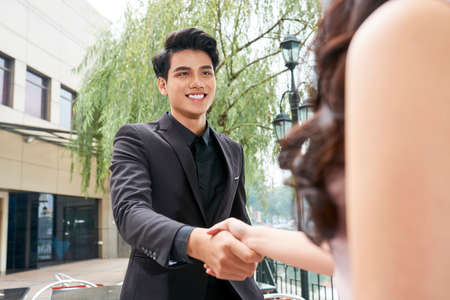 Young handsome entrepreneur shaking hand of his female coworker before meetingの写真素材
