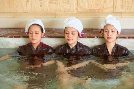 Young Asian girls relaxing in the water with eyes closed during spa procedure at spa centreの写真素材