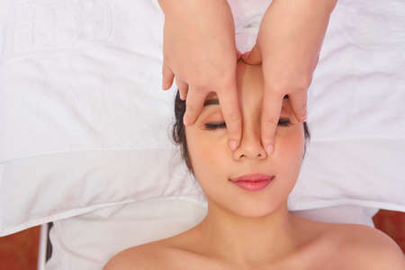 Asian beautiful woman lying on bed with eyes closed and getting spa treatment at spa salonの写真素材