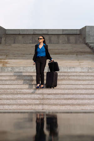 Business lady with suitcase on stepsの写真素材