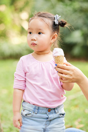 Hand of mother helping daughter to carry delicious ice cream