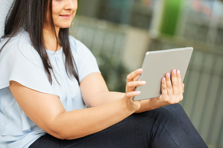 Woman sitting outdoors and watching new show episode on tablet computer