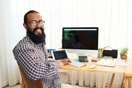 Portrait of African young programmer sitting at the table working as a freelancer and developing the...