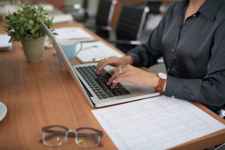Close-up of businesswoman working on laptop computer while sitting at the table in boardromm