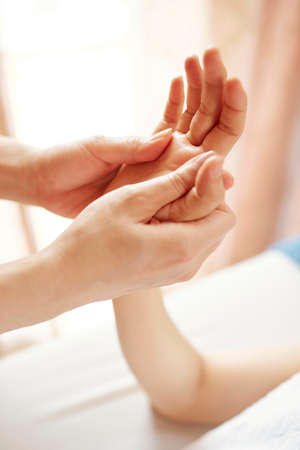 Specialist massaging certain points on hand of young womanの写真素材