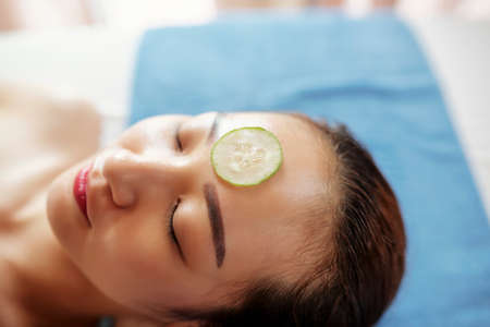 Beautiful young Asian woman with cucumber slice on foreheadの写真素材