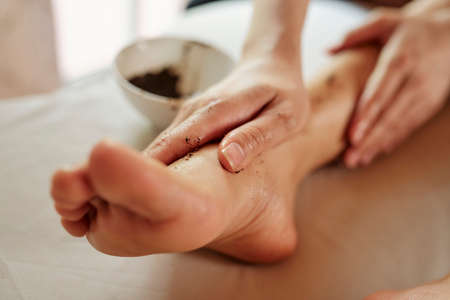 Woman applying coffee scrub on her foot and massaging itの写真素材