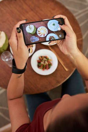 Young woman photographing tasty dishes she is having for lunchの写真素材