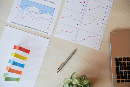 Various charts and graphs on table of financial analyst, view from above