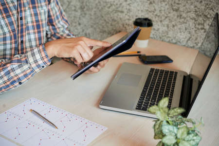 Hands of businessman sitting at his office desk and working on digital tabletの写真素材