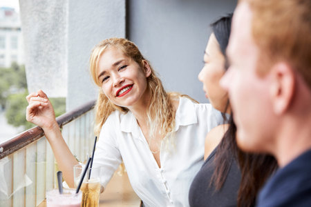 Beautiful young blond woman resting in cafe with friends