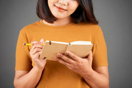 Smiling young woman writing her thoughts and ideas in plannerの写真素材