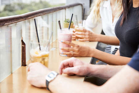 Hands of people enjoying delicious milkshakes and cocktails in cafeの写真素材