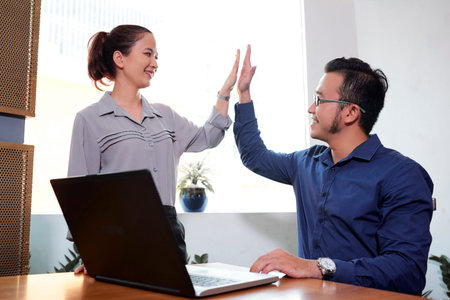 Happy Vietnaemse business colleagues giving each other high five to express unity