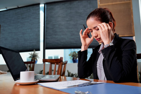 Stressed young Asian businesswoman trying to concentrate on work