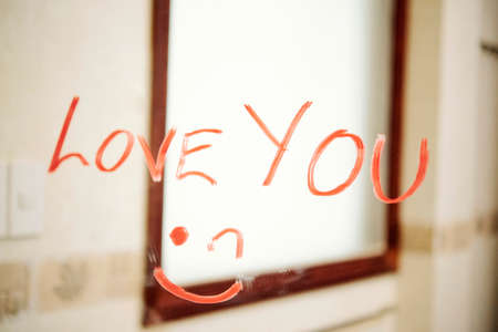 Confession of love and smiley face written with red lipstick on the mirror in bathroomの写真素材