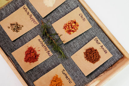 Image of different spices and herbs on the signed papers lying in the row on the board over white...