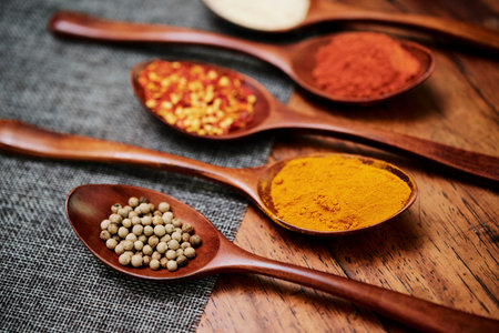 Close-up of wooden spoons with various powder spices on the table preparing for cooking meal