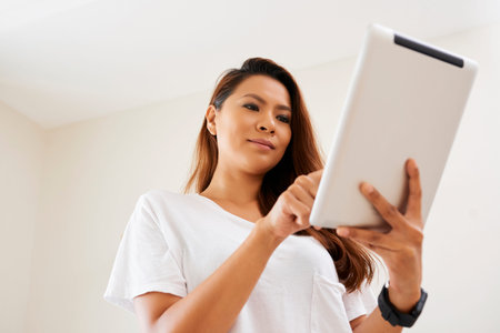 Asian young woman standing and communicating online on digital tablet