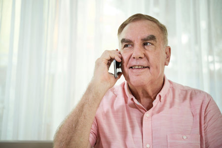 Cheerful Caucasian old man talking on phone with his grandchildrenの写真素材