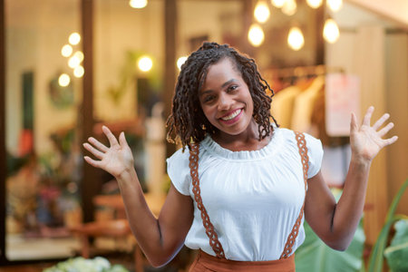 Cheerful excited young woman standing in front of store and announcing seasonal sale